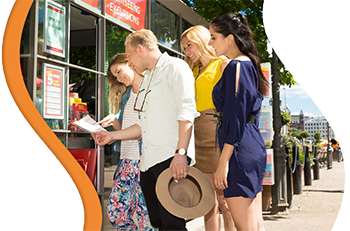 Tourists using the Helsinki Card at a ticket machine to access various attractions, including sightseeing tours, museums, and guided experiences. The card offers free entry to top attractions and best sightseeing tours, activated upon first use and valid 
